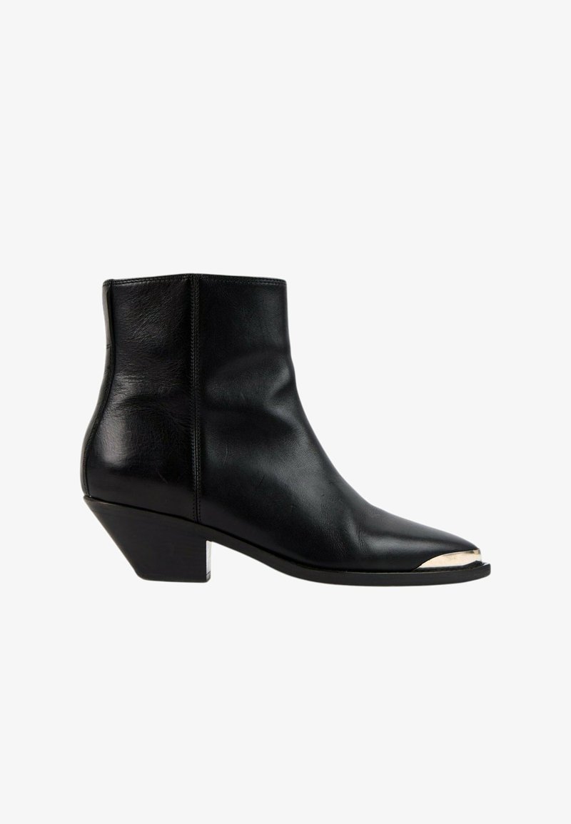 Bottine en cuir noir avec un petit talon incliné et un embout métallique argenté sur fond blanc.