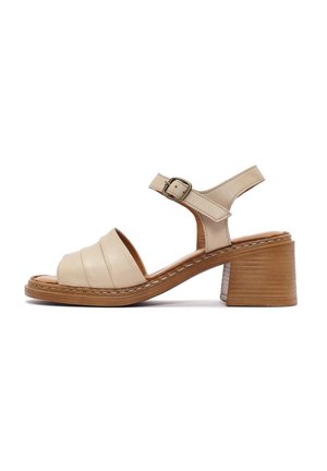 Sandalo in pelle beige con cinturini larghi e chiusura a fibbia. Presenta un tacco in legno e dettagli cuciti sulla suola.