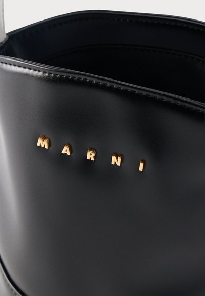 Μαύρη δερμάτινη τσάντα χειρός με χρυσά μεταλλικά γράμματα που σχηματίζουν τη λέξη "MARNI" στο πάνω μπροστινό μέρος.