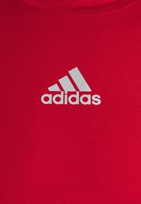 Rotes Sportshirt aus glattem Stoff mit einem weißen Adidas-Logo, das zentral auf der Brust angebracht ist. Rundhalsausschnitt, kurze Ärmel.
