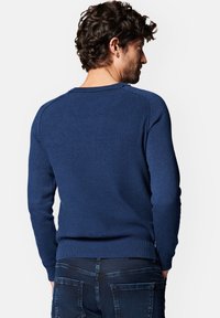 Granatowy sweter z prążkowanej tkaniny, okrągłym dekoltem i długimi rękawami, z delikatną fakturą i dopasowanymi mankietami. Widok z tyłu.