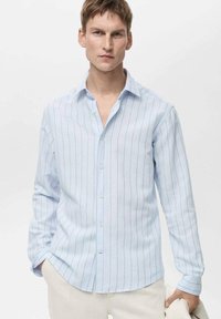 Lichtblauwe longsleeve shirt van stof met verticale witte strepen. Heeft een button-down kraag en een relaxed fit.