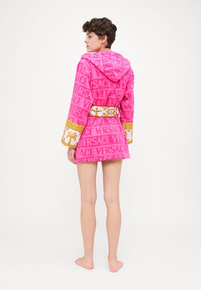 Rosa Kapuzenrobe mit "VERSACE"-Logo aus strukturiertem Stoff. Verfügt über goldene Akzente an den Ärmelbündchen und einem Gürtel. Kurze Länge endet über den Oberschenkeln.