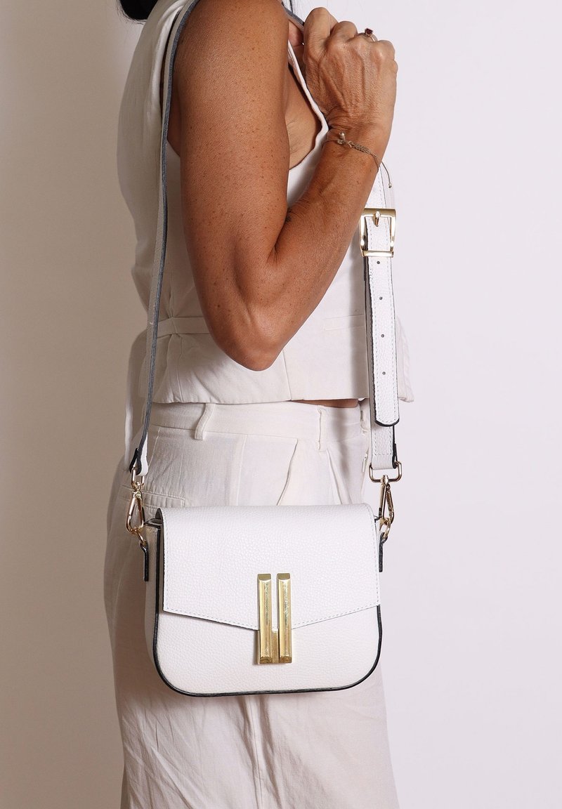 Borsa a tracolla bianca in pelle con chiusura a pattina, dettagli in metallo dorato e tracolla staccabile con bordo grigio chiaro.