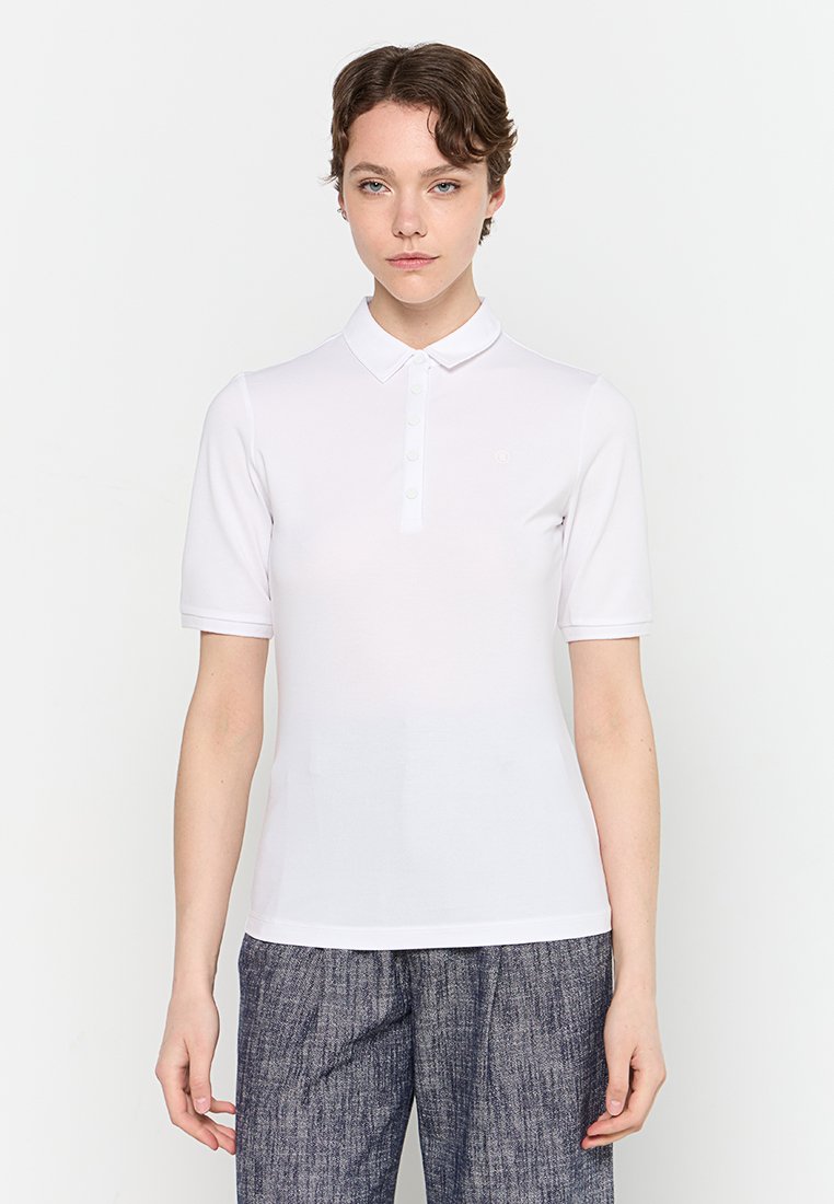 Weißes Poloshirt mit kurzen Ärmeln, mit Kragen und Knopfleiste ausgestattet, aus glattem Stoff, hat ein kleines Logo auf der Brust.