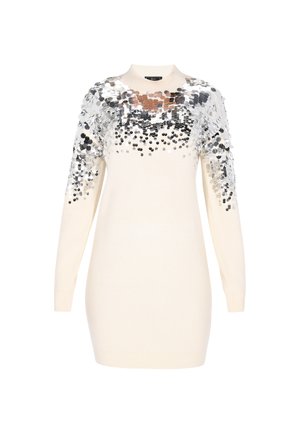 Krémszínű, hosszú ujjú kötött ruha magas nyakkal, melyet ezüst színű, csoportosított flitterek díszítenek a vállaknál és a felső mellkason.