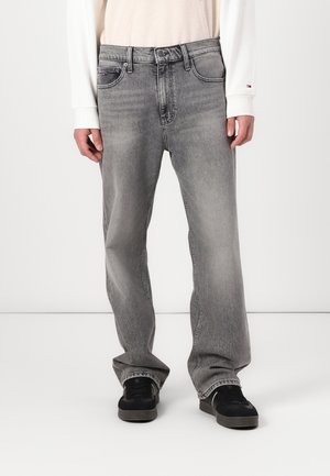 Jean en denim gris avec une coupe décontractée, design à cinq poches et décoloration subtile. Associé à des baskets noires et un haut de couleur claire.