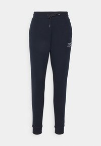 Pantaloni tuta navy con cintura elastica e cordoncino, gambe affusolate, tasche laterali e dettaglio del logo ricamato sulla coscia sinistra.