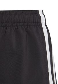 Pantalones cortos deportivos negros con cintura elástica, rayas blancas a los lados y textura de tela lisa. Detalle notable de costuras a lo largo de los costados.