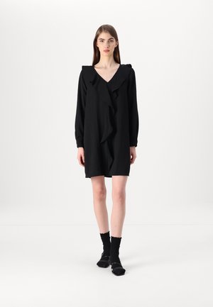 Black dress with ruffled collar and front, long sleeves, knee-length, made of soft fabric. Worn with black socks and shoes.