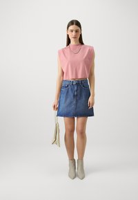 Roosa ilma varrukat crop top, sinine denim A-line seelik, beežid pahkluu saapad ja hele käsitasku. Lihtne disain ja juhuslik välimus.