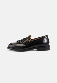 Black leather loafers with a zebra-patterned upper, featuring a tassel accent and a rounded toe, on a low stacked heel.