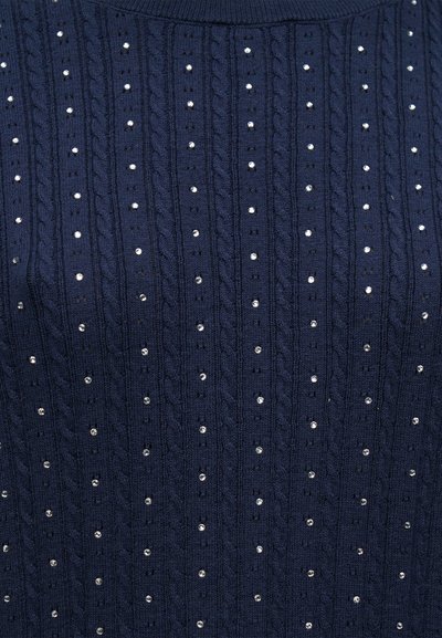 Πλεκτό ύφασμα σε ναυτικό μπλε με κάθετα σχέδια καλωδίων και ομοιόμορφα τοποθετημένες μικρές ασημένιες χάντρες σε σειρές.