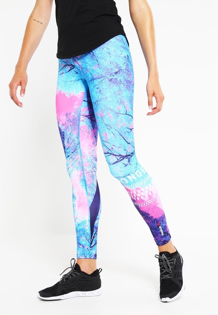 Färgglada atletiska leggings i blått med rosa och lila trämönster. Tillverkade av elastiskt material, har en åtsittande design och logotypdetaljer.