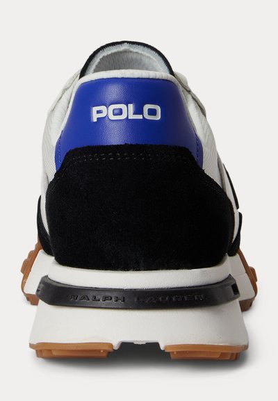 Rückansicht eines weißen Sneakers mit schwarzem Wildlederabsatz, einem blauen Lederpaneel mit der Aufschrift "POLO" und "RALPH LAUREN" auf dem schwarzen Mittelsohlenband.