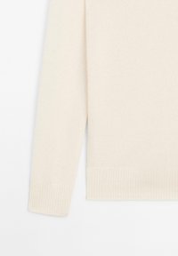 Maglione color crema con una texture morbida. Presenta un orlo e polsini a coste, evidenziando un design semplice e minimalista.