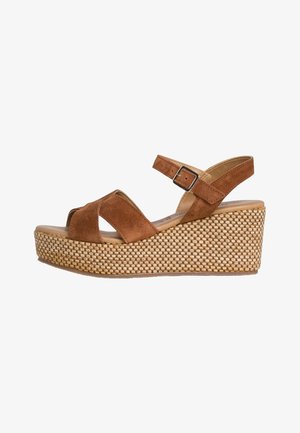 Sandale compensée en suède marron à larges brides croisées, boucle à la cheville et semelle plateforme tissée texturée.