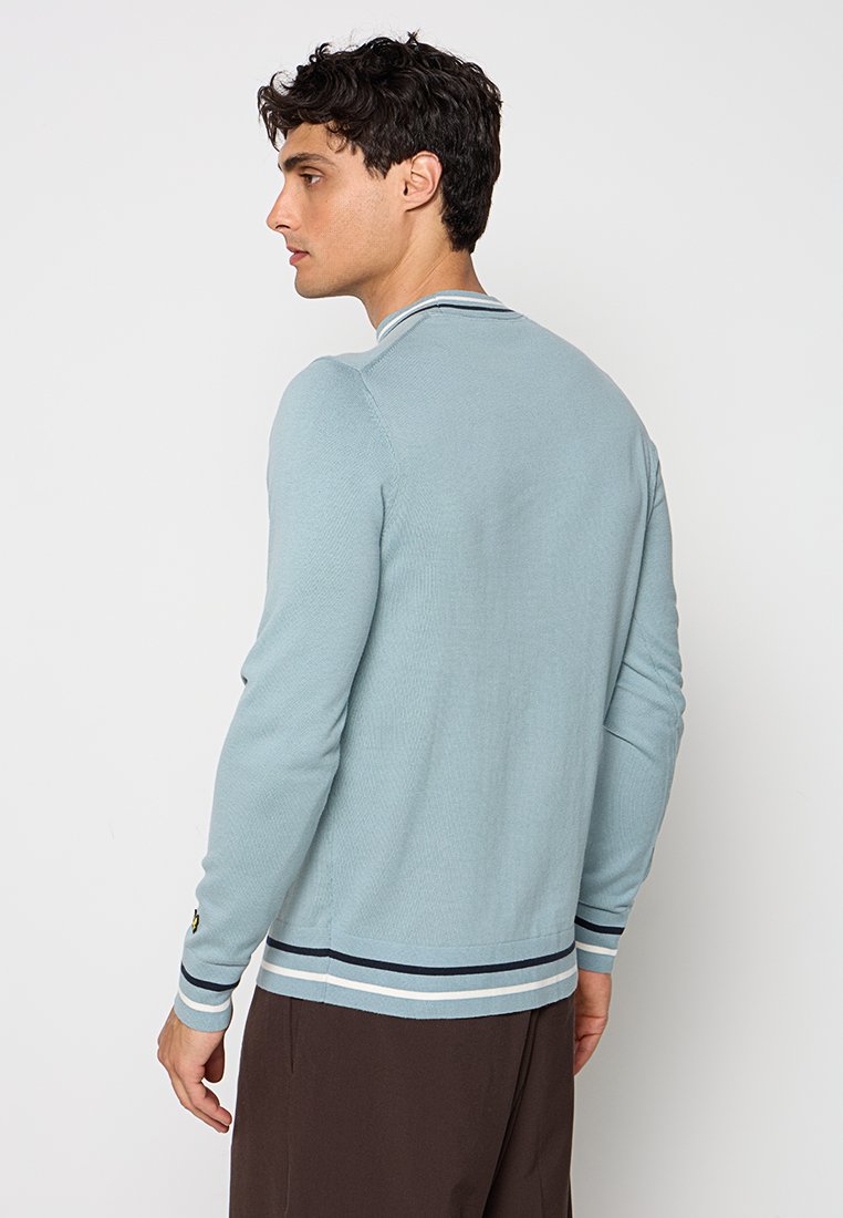 Cardigan a maglia di colore azzurro chiaro con colletto rotondo, dettagli a righe blu navy e bianche orlati in fondo e ai polsini, e un tessuto strutturato.