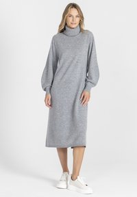Szara dzianinowa sukienka z wysokim kołnierzem, balonowymi rękawami i prostym krojem. W zestawieniu z białymi platformowymi sneakersami dla kontrastu.