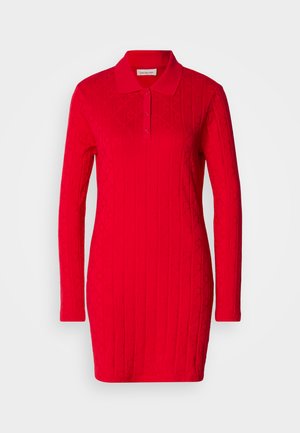 Robe polo rouge à manches longues, motif texturé avec des diamants et des cœurs en relief, et un col classique avec fermeture à boutons.