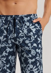 Pantaloni corti blu navy con motivo floreale in azzurro chiaro, vita elastica con cordoncino, e tasche laterali.