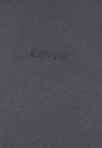 T-shirt grigio scuro a maniche corte in cotone con superficie testurizzata e logo "Levi's" in rilievo dello stesso colore sulla parte anteriore.