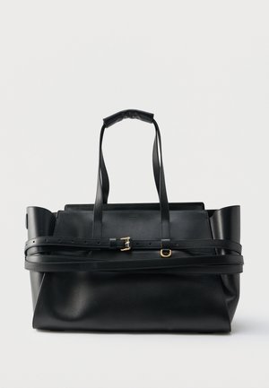 Μαύρη δερμάτινη τσάντα tote με διπλές επάνω λαβές, ρυθμιζόμενη ζώνη τυλιγμένη γύρω και εξαρτήματα με χρυσό τόνο, σε λευκό φόντο.
