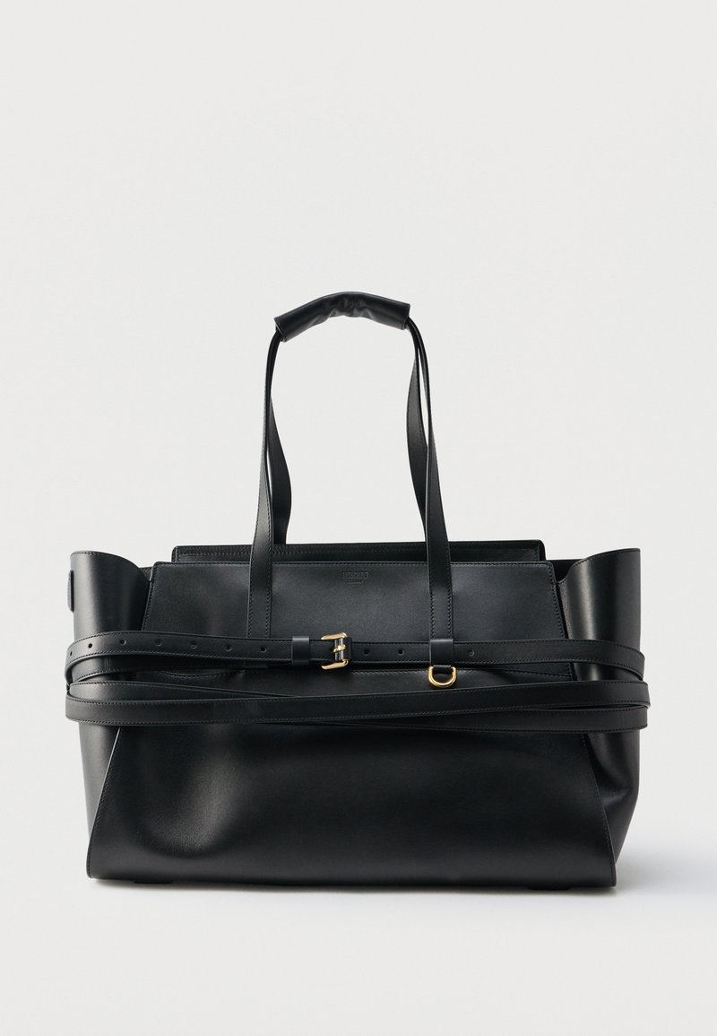 Μαύρη δερμάτινη τσάντα tote με διπλές επάνω λαβές, ρυθμιζόμενη ζώνη τυλιγμένη γύρω και εξαρτήματα με χρυσό τόνο, σε λευκό φόντο.