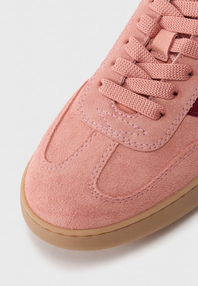 Baskets en daim rose doux avec une surface texturée, bout rond et lacets plats. Caractérisées par une semelle en caoutchouc brun clair et des accents contrastants.