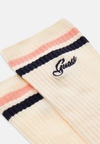 Kousen tot net onder de knie met ribbelpatroon in crème met marineblauwe en roze strepen; met geborduurd "Guess"-logo. Zachte textuur, casual ontwerp.