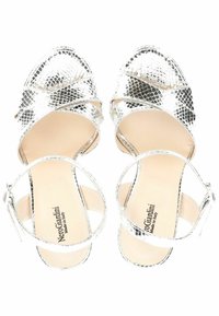 Sandales argentées avec un design à lanières croisées, dessus métallique texturé et semelle intérieure beige lisse. Présente une sangle de cheville avec une boucle.