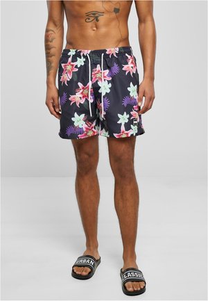 Shorts de bain noirs avec un motif floral vibrant comprenant des lys roses et des accents verts. Comprend une taille élastique et un détail de cordon.