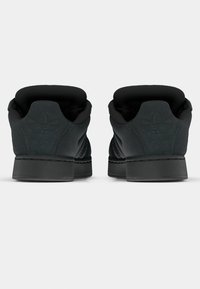 Czarne trampki z teksturowaną górą z zamszu, wyściełanym kołnierzem i formowaną gumową podeszwą. Charakteryzują się subtelnym brandingiem na pięcie i bocznych panelach.