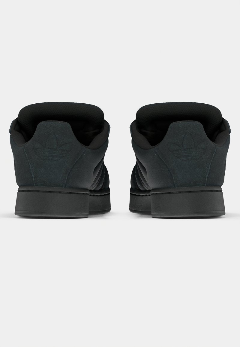 Baskets noires avec une tige en daim texturé, un col rembourré et une semelle en caoutchouc moulée. Présentent un marquage discret sur le talon et les côtés.