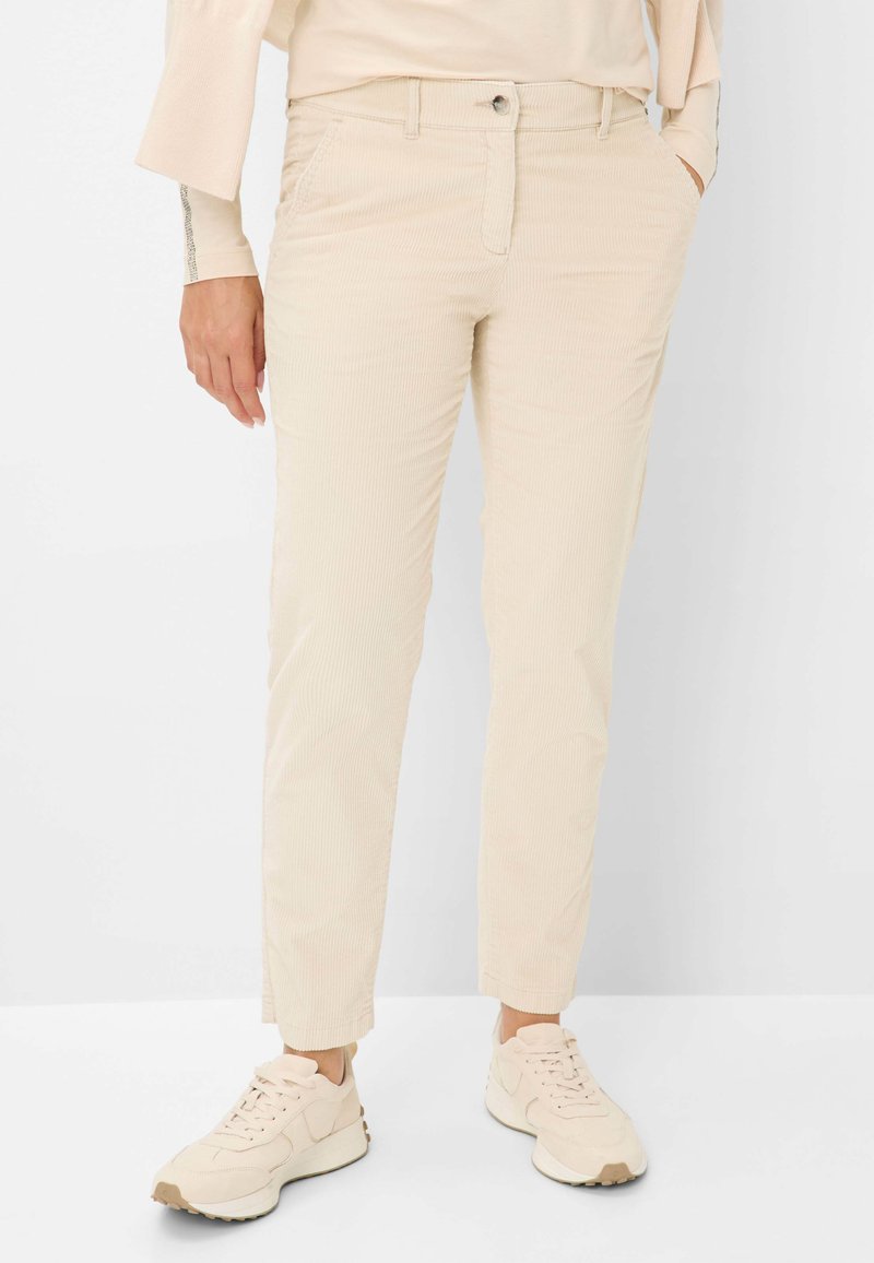 Beige corduroy broek met een rechte snit, voorzien van voorzakken, een knoopsluiting en een gladde textuur. G gedragen met lichtgekleurde sneakers.