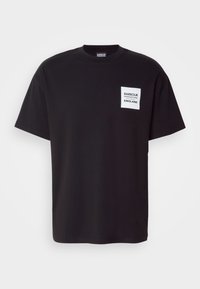 Zwarte katoenen T-shirt met een ronde hals. Heeft een witte vierkante patch met de tekst "Barbour England". Ontspannen pasvorm en korte mouwen.