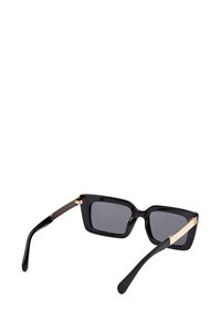 Sorte rektangulære solbriller med mørke linser og guld detaljer ved stængerne, vist fra en let skrå bagud-vinkel.