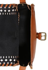 Karamellfarbene Leder-Umhängetasche mit ausgeschnittenem Design entlang des oberen Randes, schwarzer Stoffauskleidung und Messing-Schnallen-Detail.