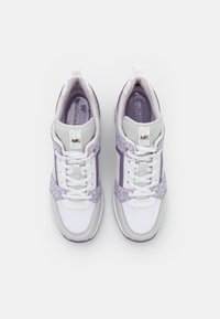 Białe i jasnofioletowe sneakersy z siateczki, skórzanymi akcentami oraz wzorzystymi bocznymi bokami. Posiadają zaokrąglony czubek, wyściółkę wokół kostki oraz sznurówki.