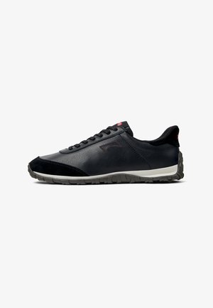 Chaussures de sport noires en cuir et daim, dotées d'une semelle rembourrée, d'une fermeture à lacets et d'une tige texturée avec des accents subtils.