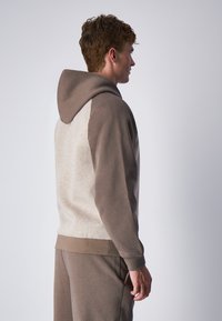 Felpa con cappuccio caratterizzata da un corpo beige e maniche marroni scure, con polsini e orlo a costine, realizzata in un morbido tessuto testurizzato.