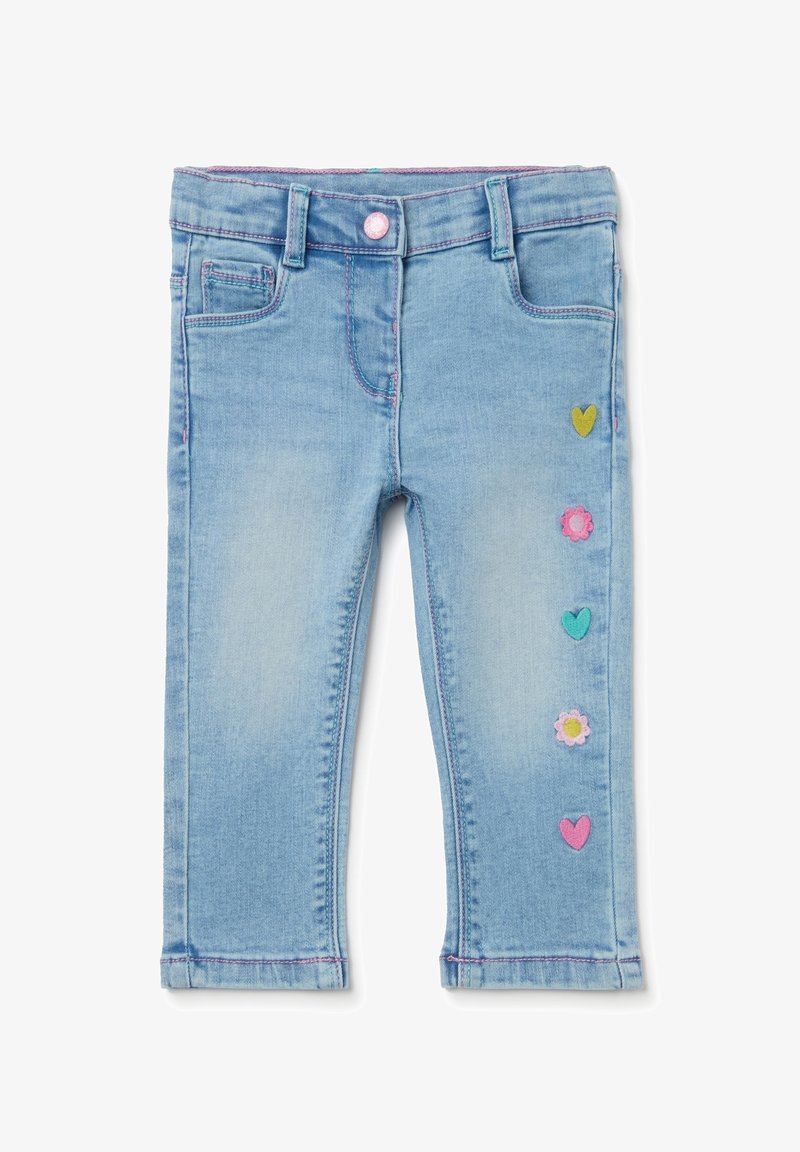 Jeans azzurri chiaro per bambini piccoli con cuciture rosa e toppe colorate a forma di cuore e fiore su una gamba.