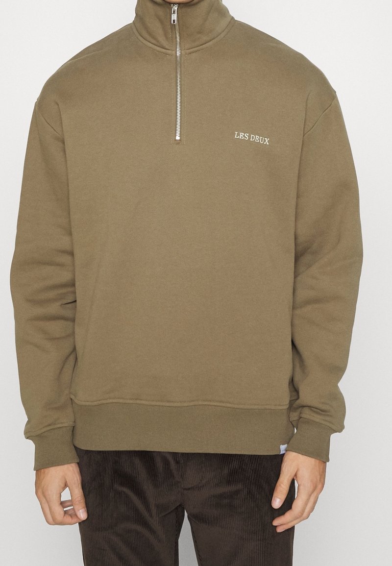 Sweatshirt olive vert à fermeture éclair quart, fabriqué en tissu doux en mélange de coton. Présente des coutures ton sur ton et un logo brodé "LES DEUX" sur la poitrine.