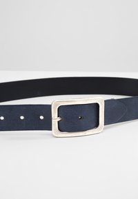 Donkerblauwe leren riem met een rechthoekige zilveren metalen gesp, voorzien van meerdere gaatjes voor verstelbaarheid en een gladde textuur door de hele riem.