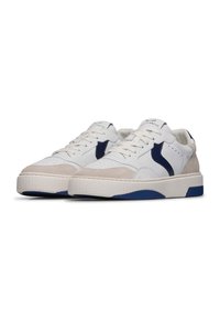Sneaker bianche e beige con tomaia testurizzata, dettagli blu navy, punta forata e suola in gomma con una suola esterna blu a contrasto.