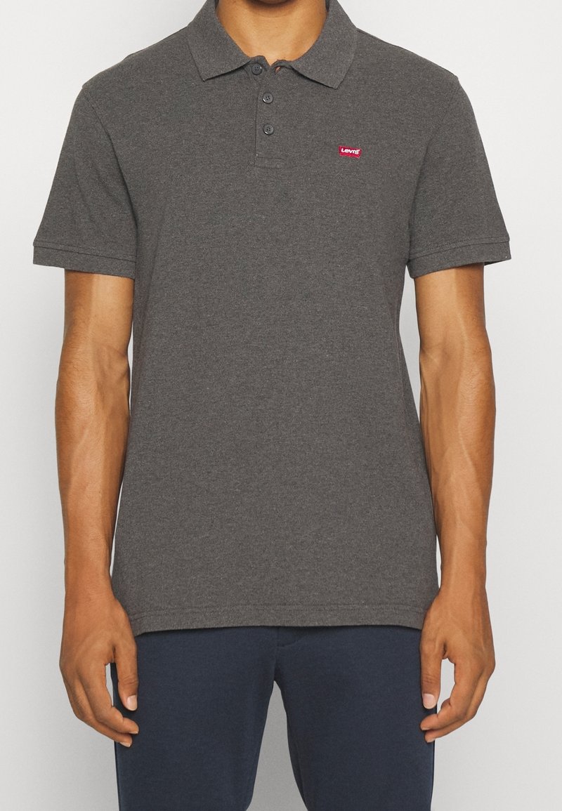 Grijze polo shirt gemaakt van katoen, met een drieknopenpatte en een klein rood Levi's-logo op de linkerborst. Ontwerp met korte mouwen.