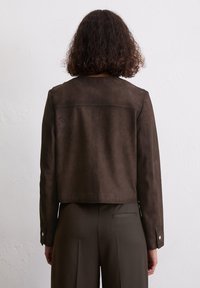 Braune Wildlederjacke mit einem cropped Design, langen Ärmeln und silbernen Hardwareelementen sowie einer glatten Textur. Minimalistische Nähte auf der Rückseite.