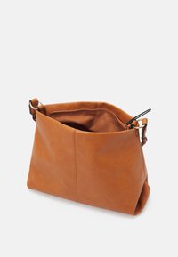Brązowa skórzana torebka o miękkim kształcie, prostokątnym fasonie i pojedynczym regulowanym pasku. Wnętrze wyściełane jest dopasowaną tkaniną.