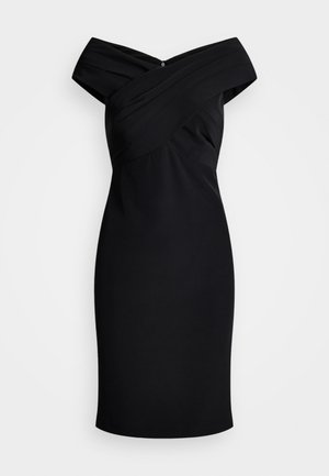 Robe noire décolletée avec une silhouette ajustée, un tissu texturé, un corsage drapé et un petit accent décoratif à l'arrière.