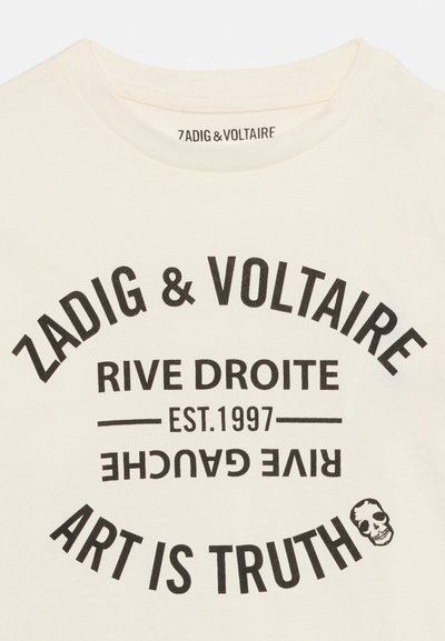Κρέμ πουκάμισο με μαύρο κείμενο που αναγράφει «Zadig & Voltaire», «Rive Droite», «Est. 1997», ανεστραμμένο «Rive Gauche» και «Το Τέχνη είναι Αλήθεια» με ένα εικονίδιο κρανίου.